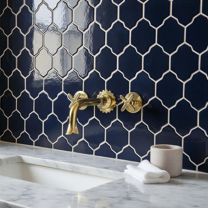 Bathroom with navy hexagonal tiles, gold faucet, and marble countertop.