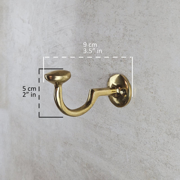 Gold wall hook with measurements on a gray concrete background