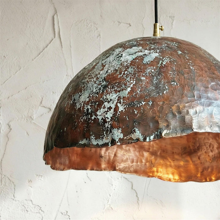 Copper pendant light with patina finish on a white wall