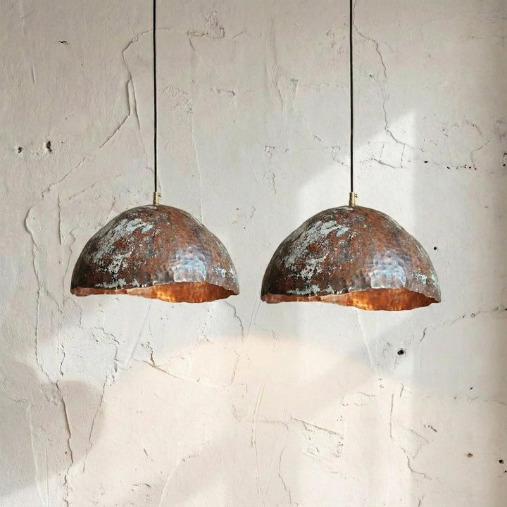 Two rustic pendant lights hanging against a textured white wall.