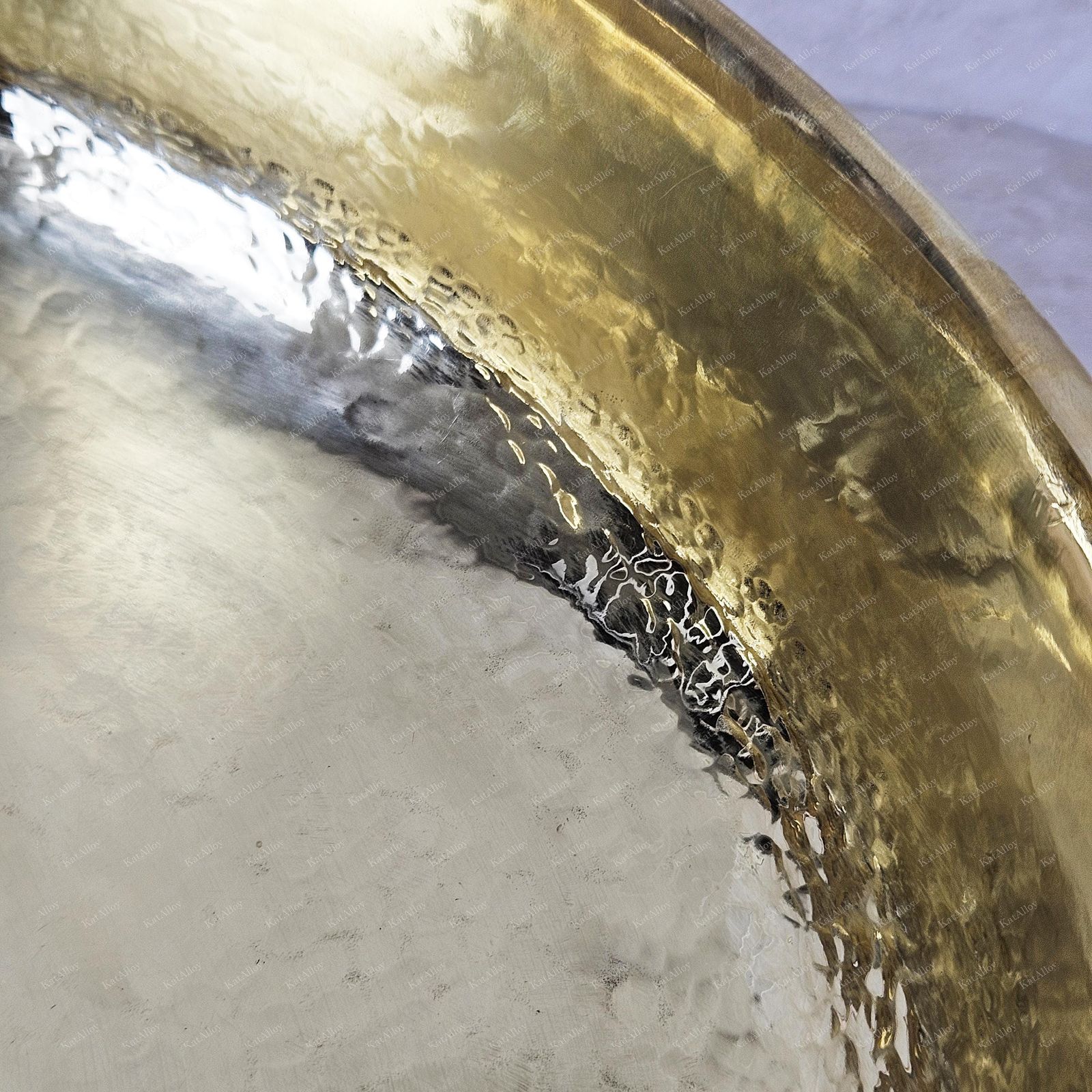 Close-up of a brass instrument with a worn surface on a gray background
