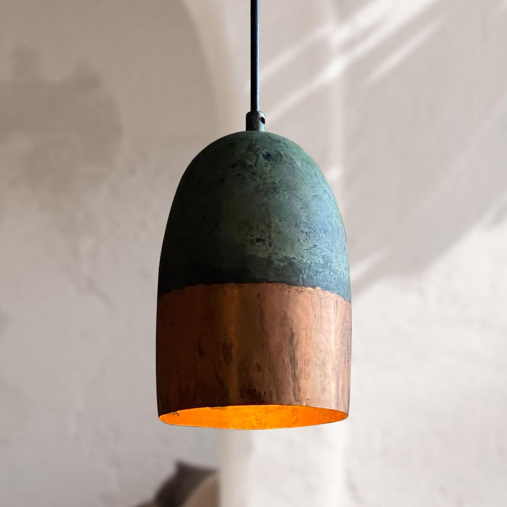 Pendant light with green top and wooden bottom on a neutral background