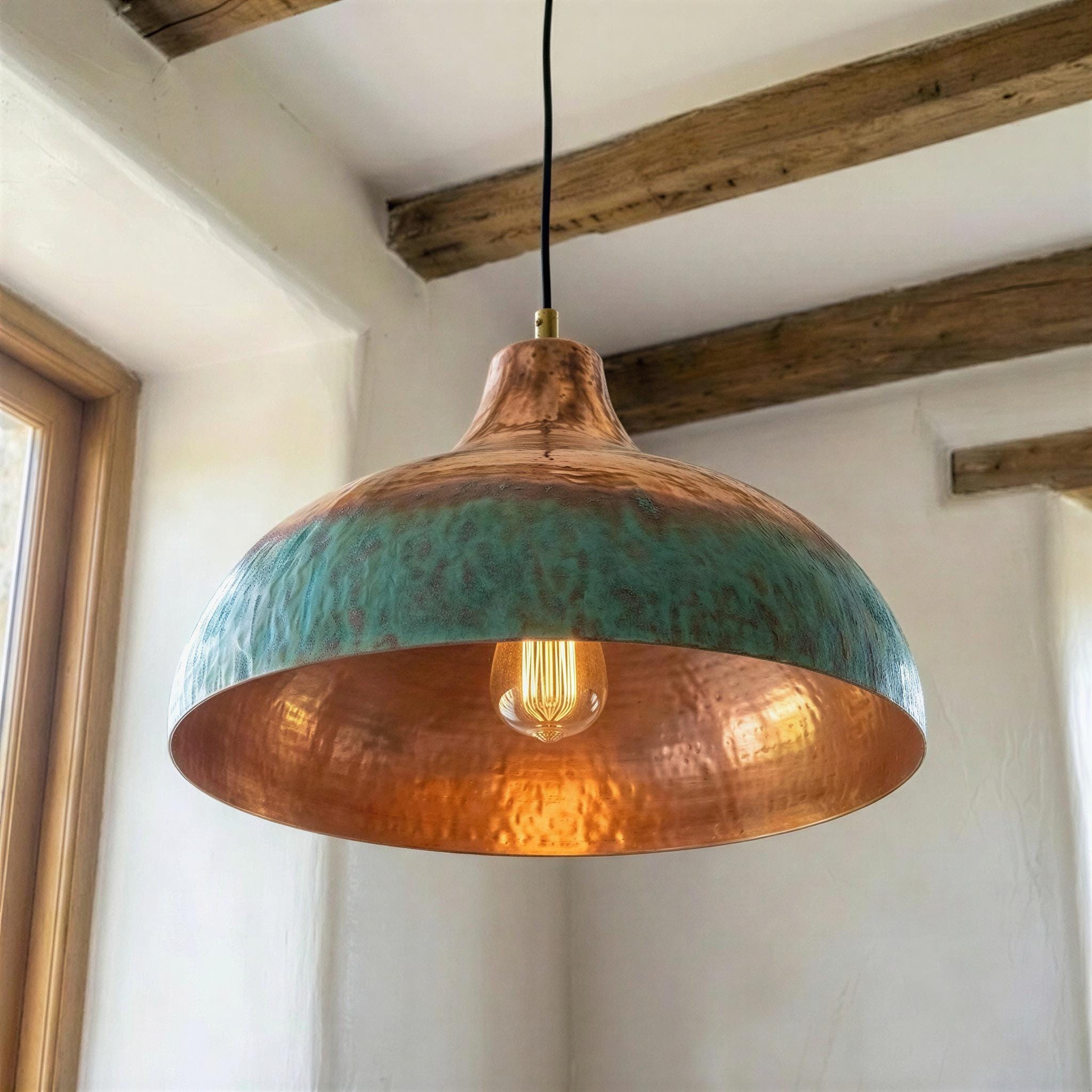 Copper and teal pendant light hanging in a room with wooden beams.