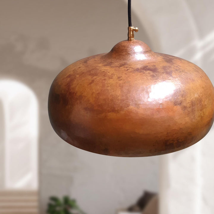 Bronze pendant light hanging against a neutral background