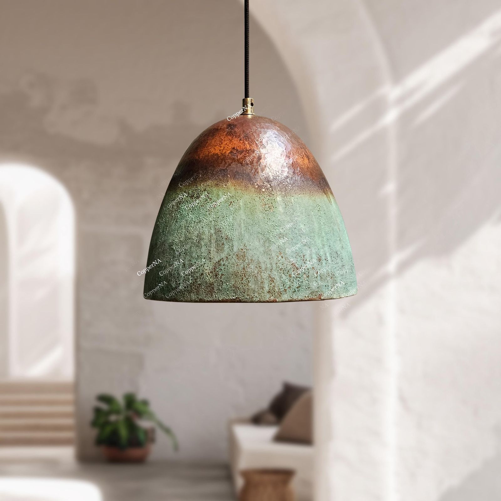 A dome-shaped pendant light with a rustic, hand-painted ceramic finish, featuring a gradient from copper-brown at the top to a textured green at the bottom, hanging in a softly lit, modern interior.