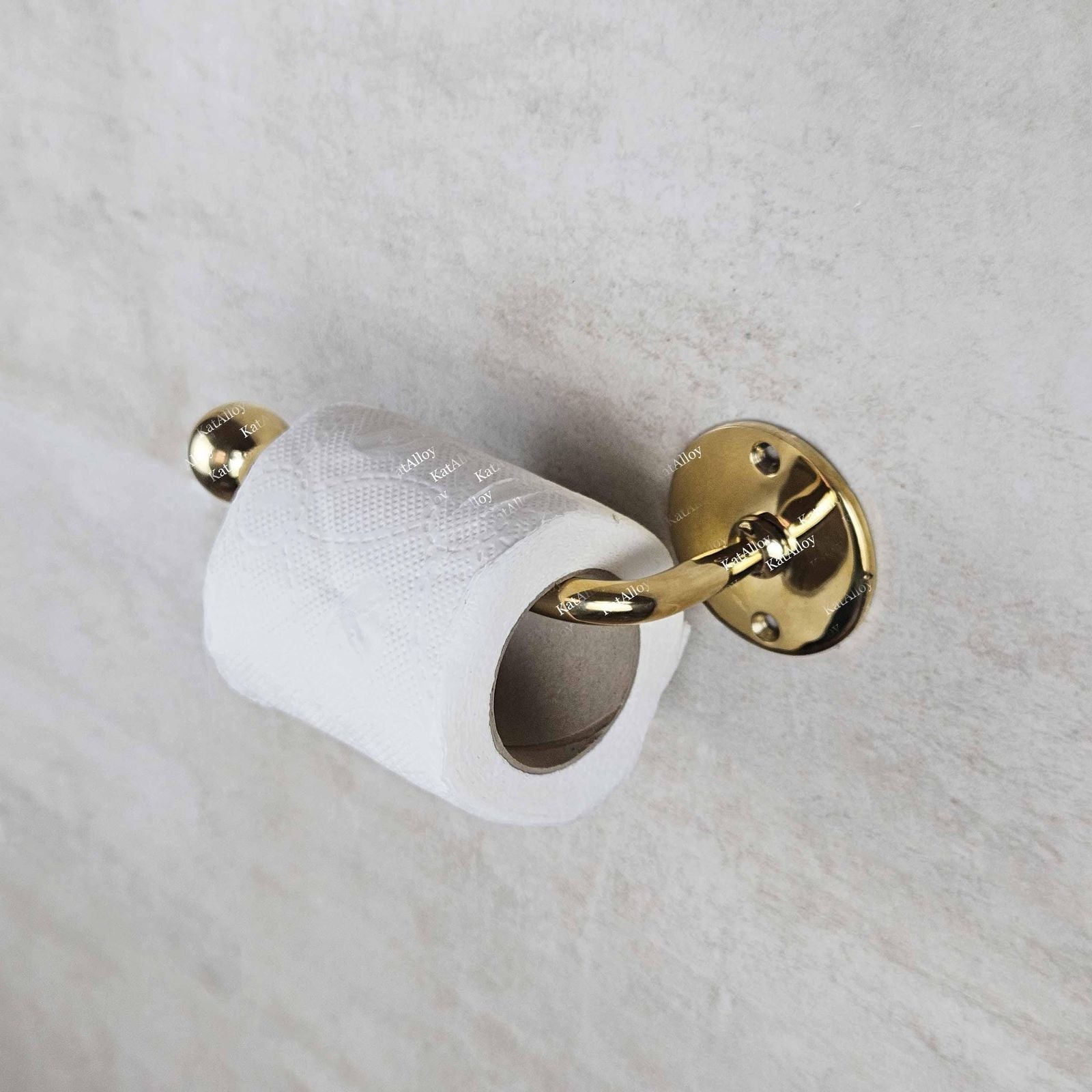 Gold toilet paper holder with a roll of toilet paper on a white marble surface