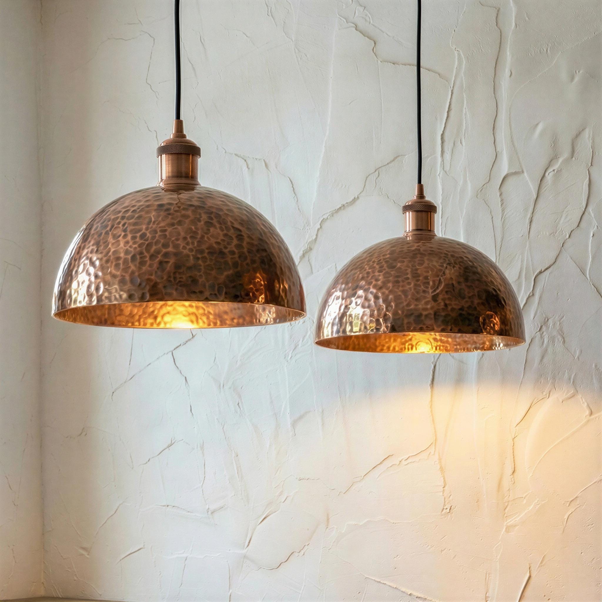 Two copper pendant lights hanging against a textured white wall.