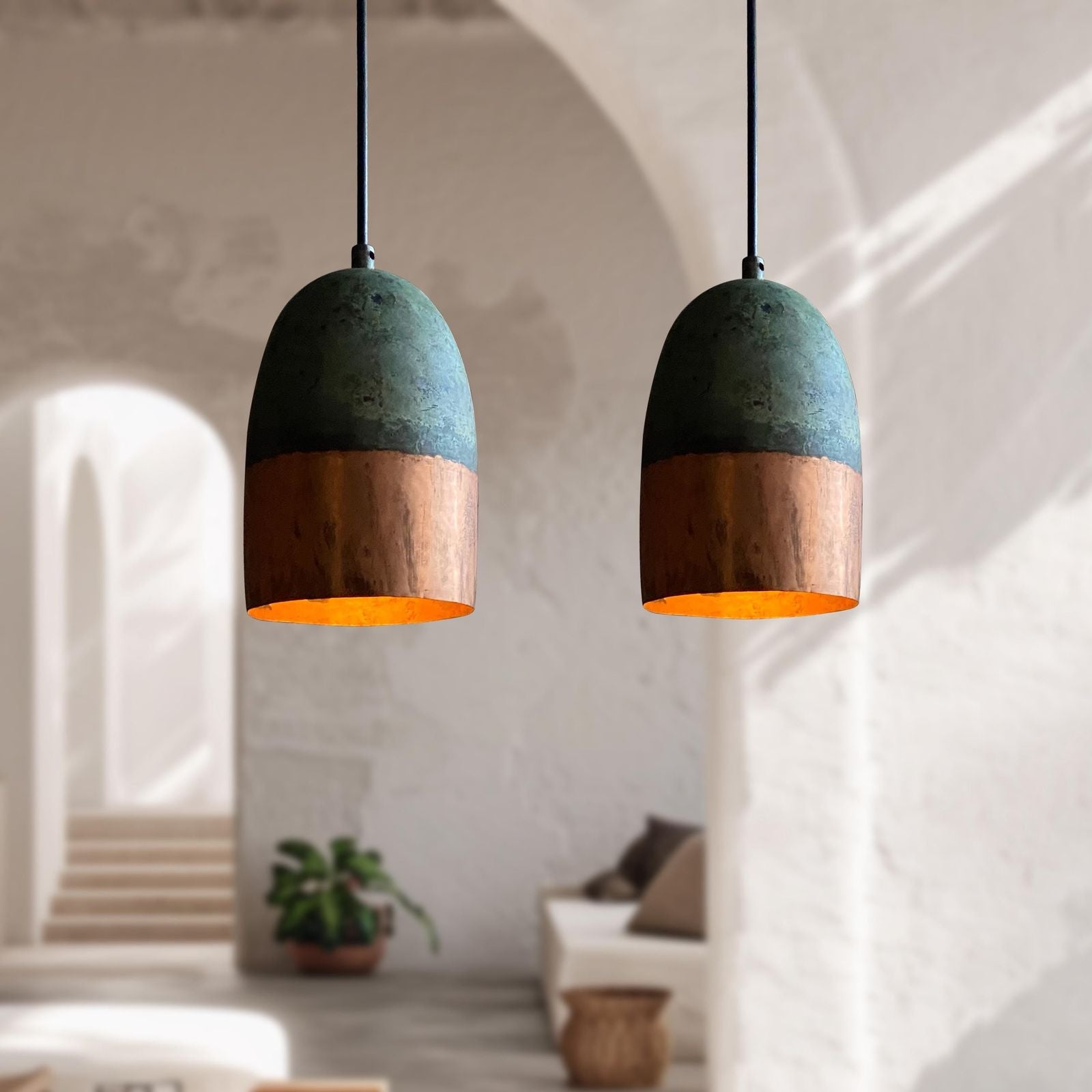 Two pendant lights with green and copper design hanging in a room.