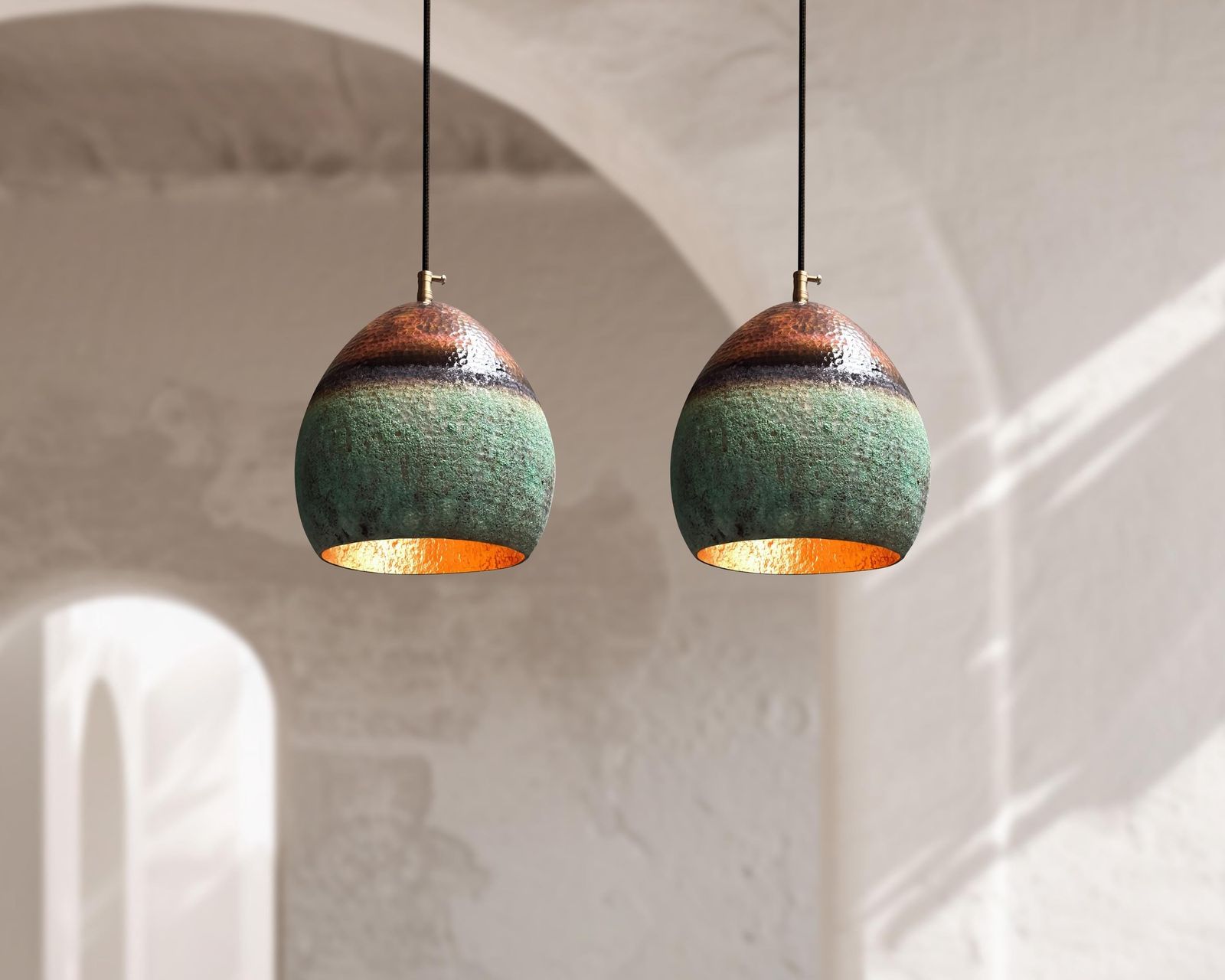 Two hanging ceramic lamps with green and gold finish on a neutral background