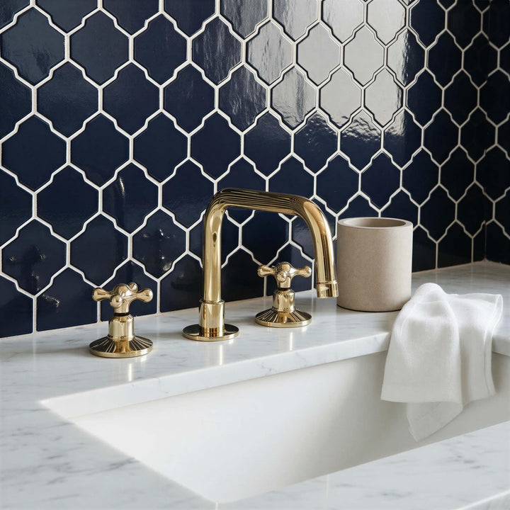 Bathroom with gold faucet and fixtures against a dark blue tiled wall.