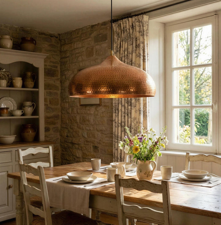 Dining room with a wooden table set for a meal, featuring a copper pendant light and a window with natural light.