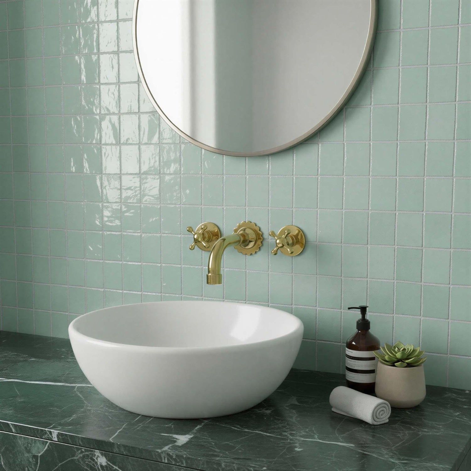 Bathroom with green tiled walls, white sink, gold faucet, and decorative items.