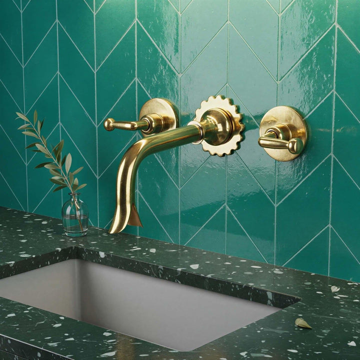 Gold faucet and handles on a teal tiled wall with a green speckled countertop.
