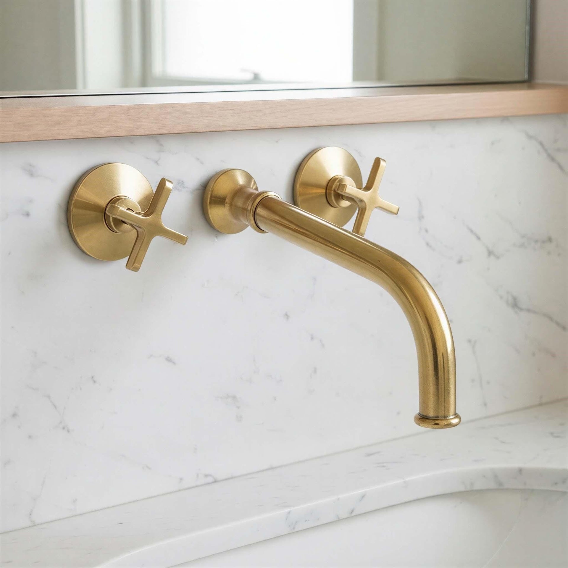 Gold faucet and handles on a marble bathroom wall