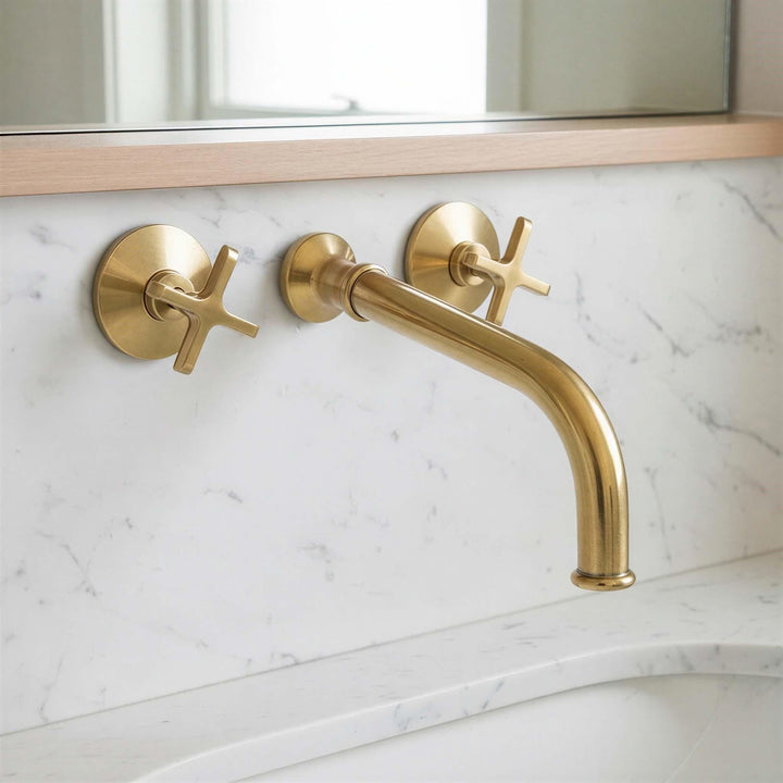 Gold faucet and handles on a marble bathroom wall