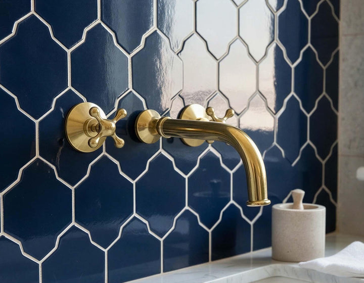 Gold faucet on a blue tiled wall with a decorative pattern