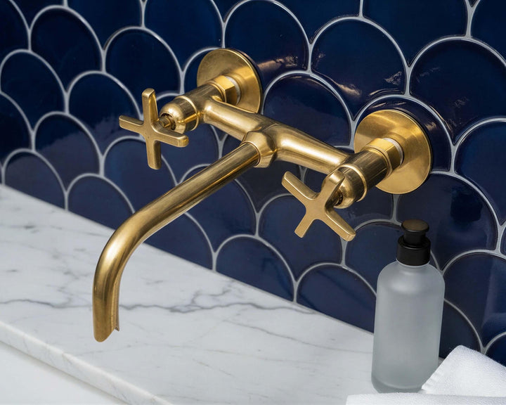 Gold faucet on a blue tiled wall with a white countertop