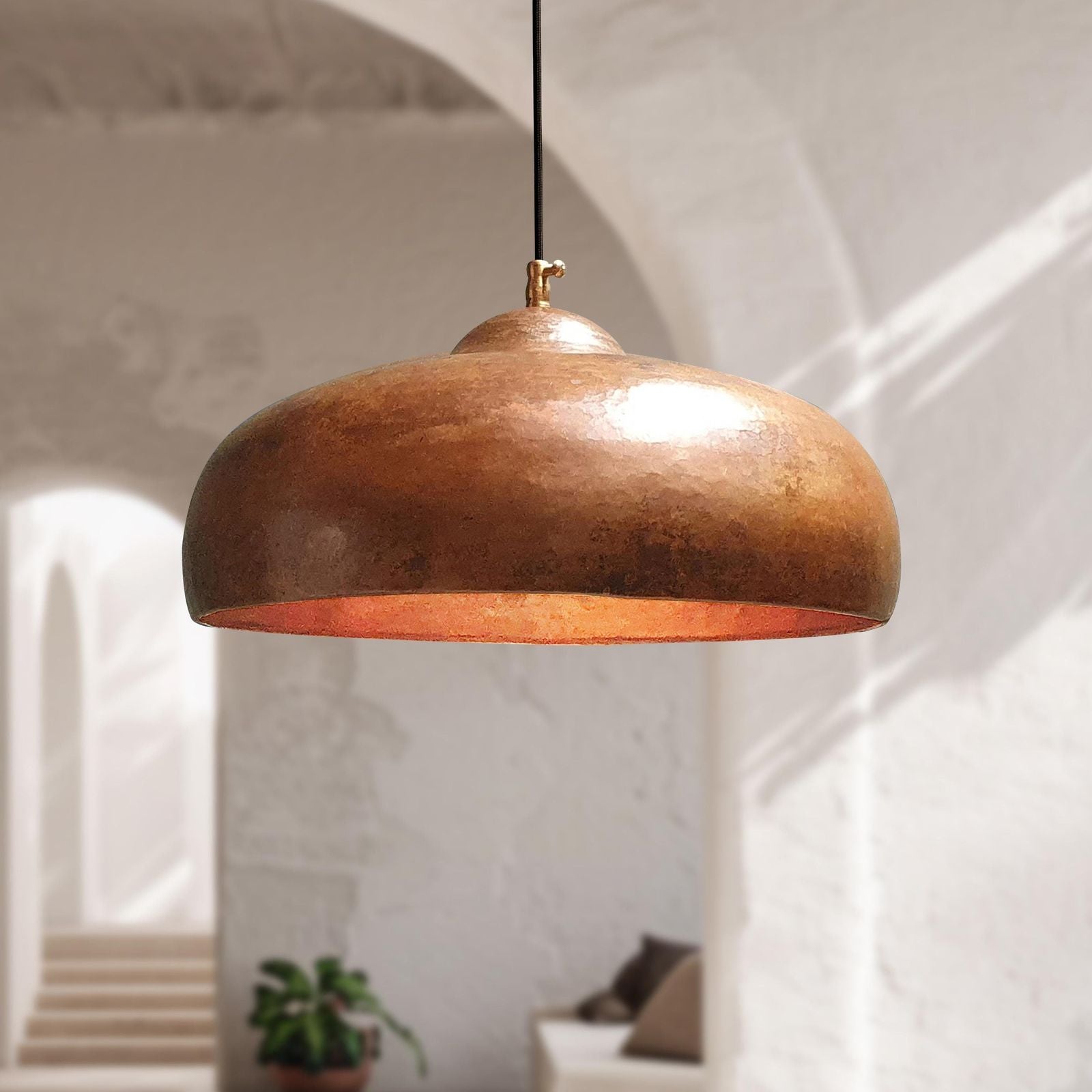 Bronze pendant light hanging in a room with white walls and minimal decor.