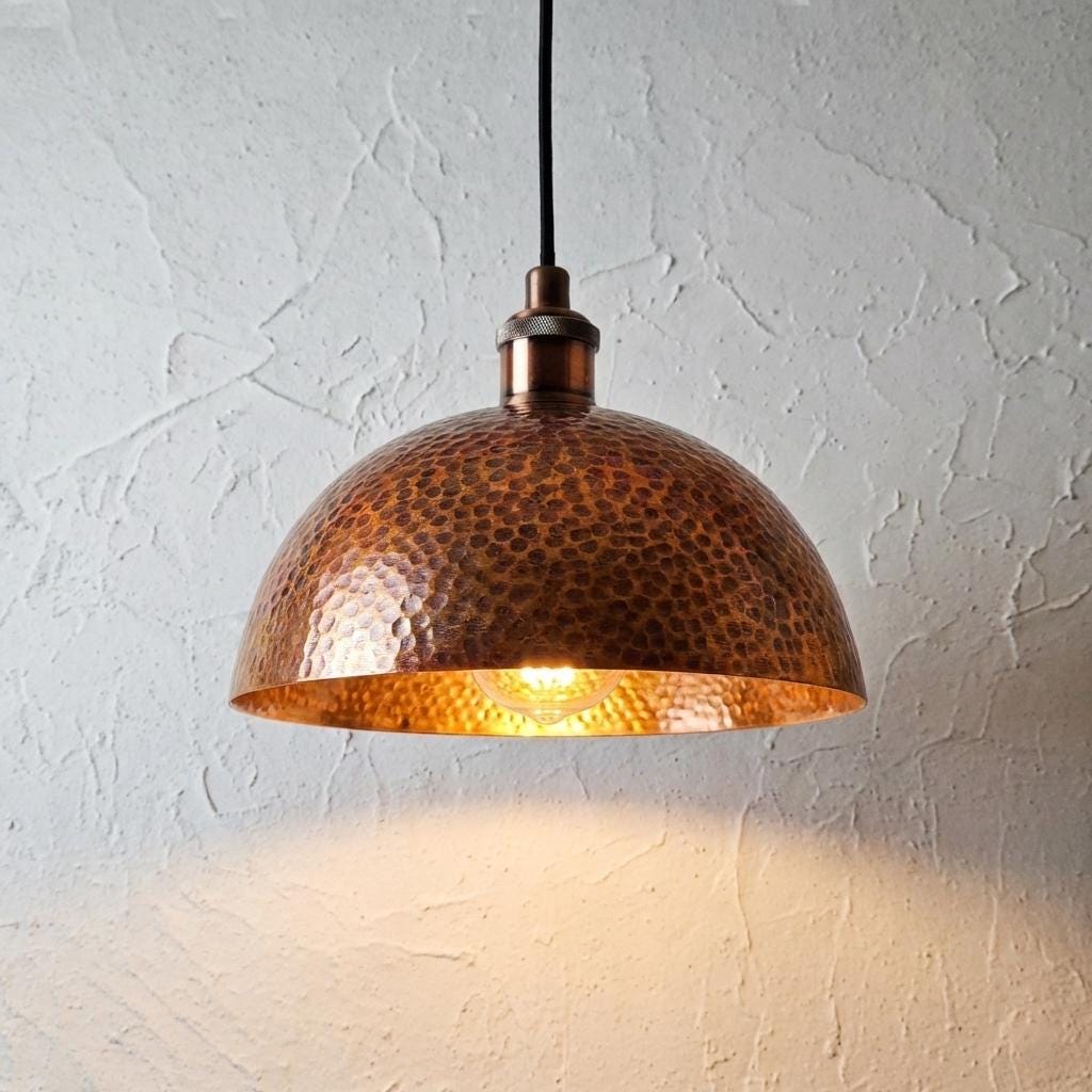 Copper pendant light hanging against a textured white wall