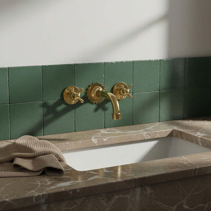Bathroom sink with gold faucet and green tiled wall