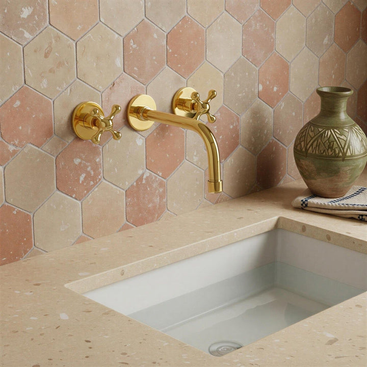 Bathroom sink with gold faucet against a hexagonal tile wall.