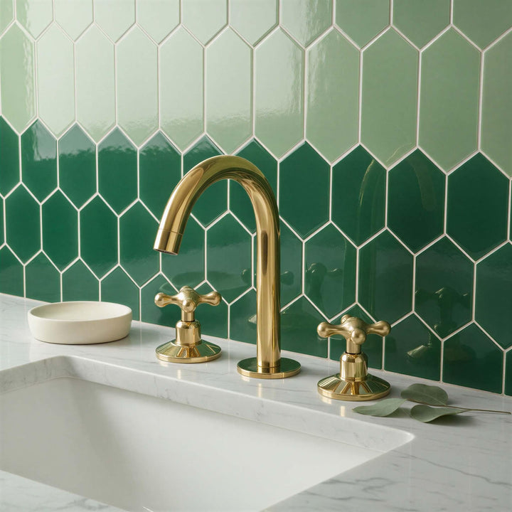 Gold faucet and handles on a kitchen sink with green tiled wall