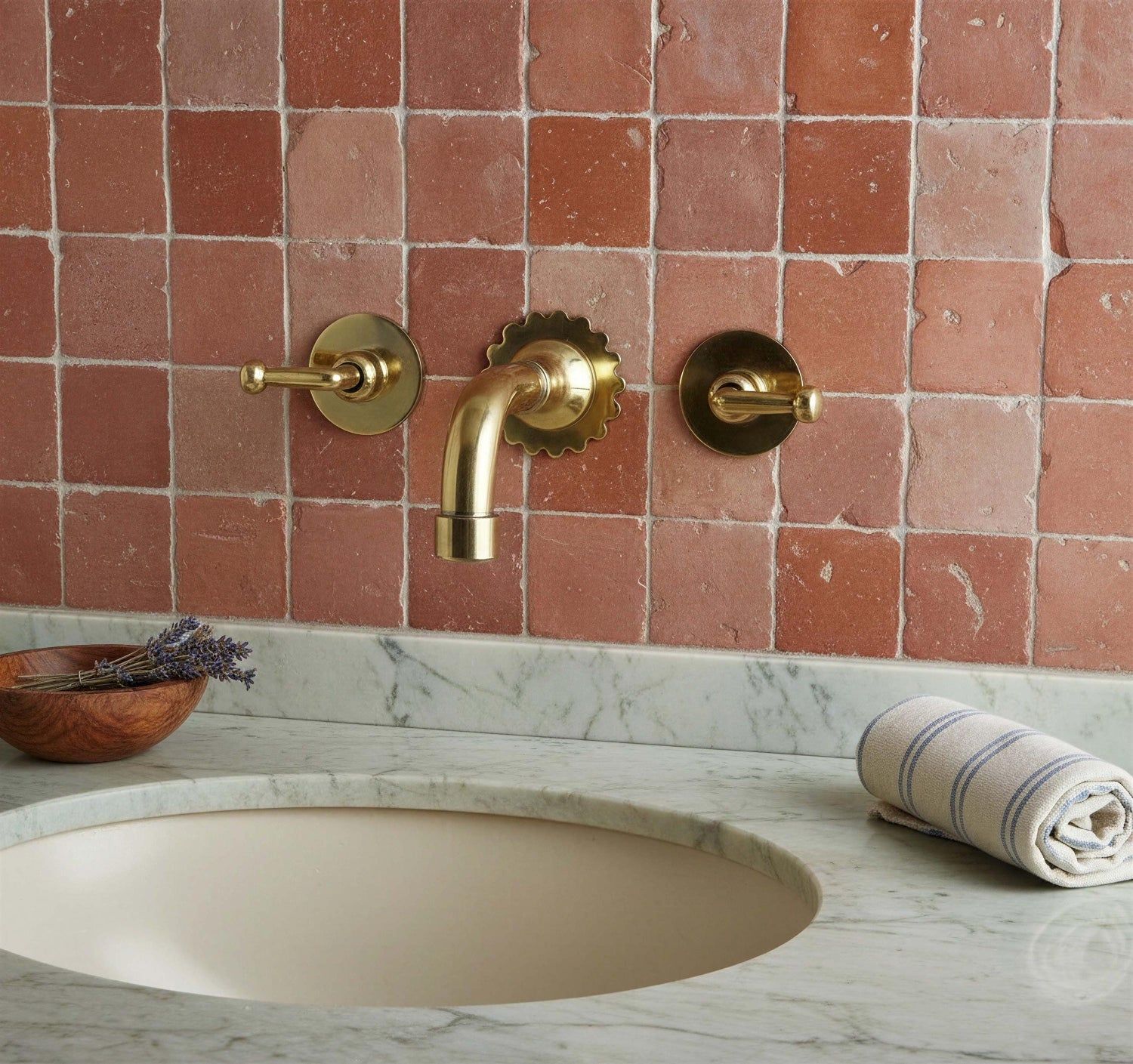 Bathroom sink with gold fixtures against a tiled wall.