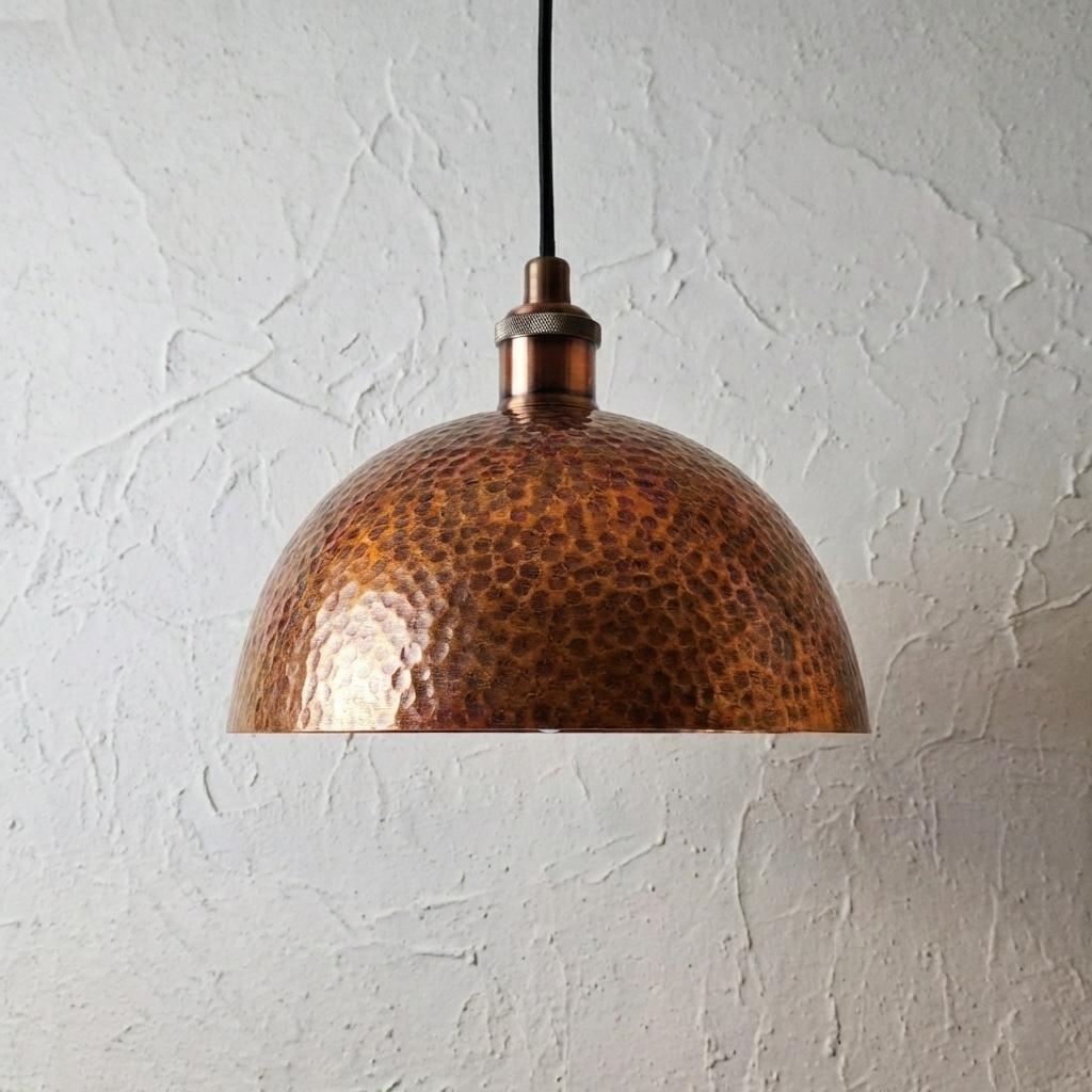 Copper pendant light against a textured white wall