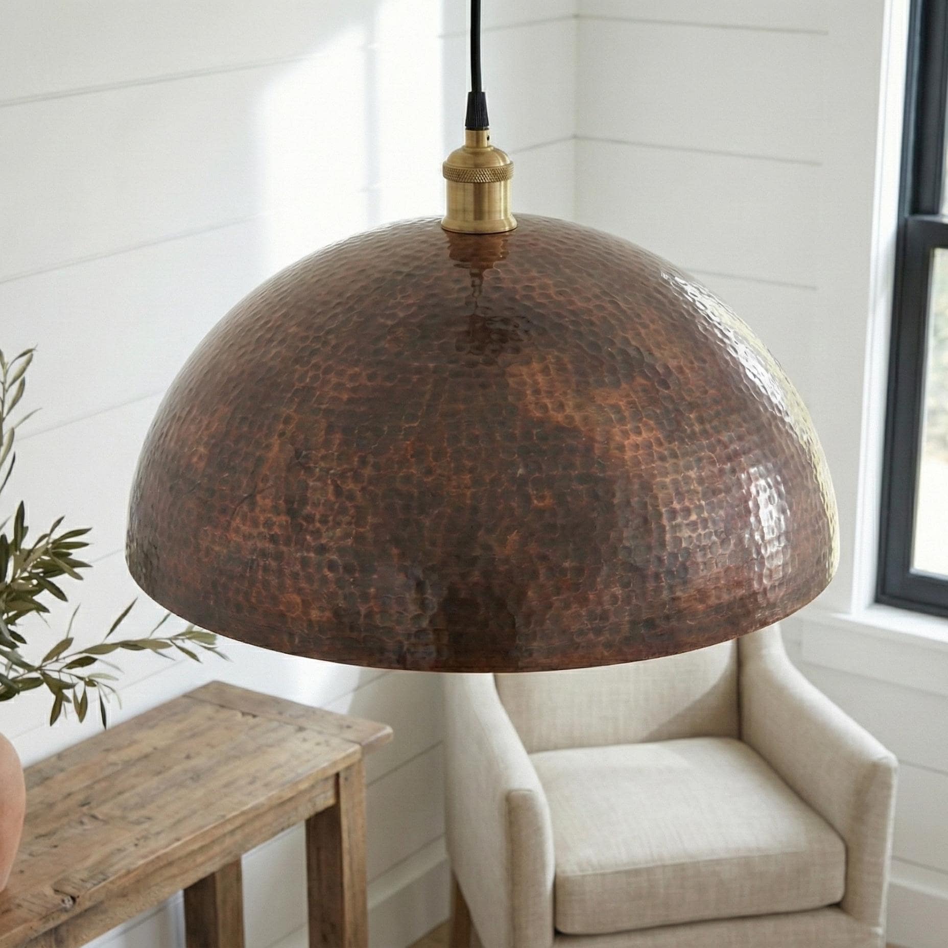 Hammered copper pendant light in a room with a chair and wooden table.