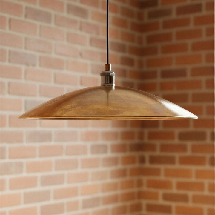 Bronze pendant light hanging against a brick wall