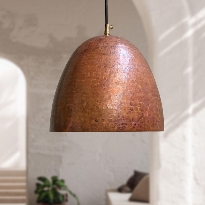 Copper pendant light hanging in a room with a neutral background