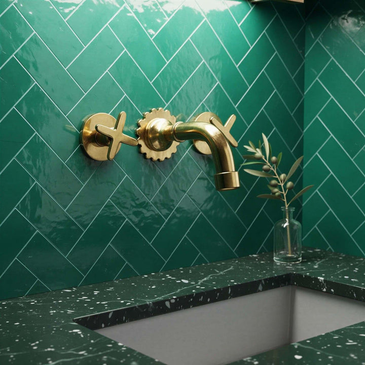 Gold faucet on a green tiled wall with a green countertop.