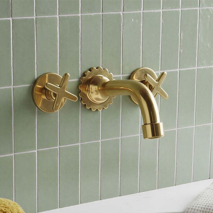 Gold faucet and handles on a green tiled wall