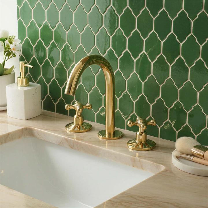 Bathroom sink with gold faucet and green tiled wall