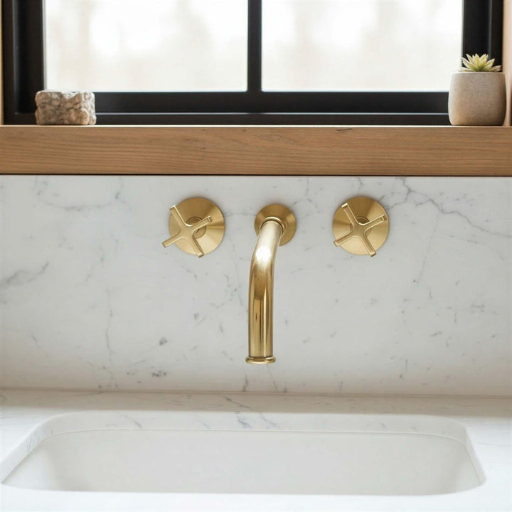 Gold faucet and handles on a marble countertop with a window in the background.