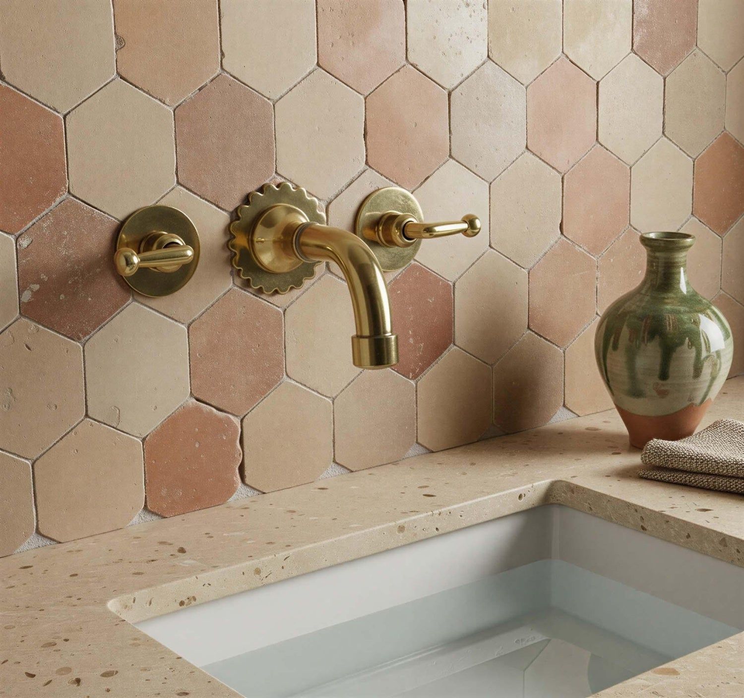 Bathroom with hexagonal tiles, gold faucet, and ceramic sink.